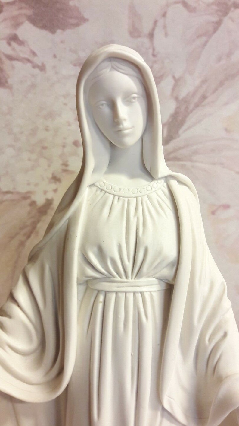 Puede incluir: Estatua de yeso blanco de la Virgen Mar&iacute;a, con una larga t&uacute;nica y un velo. La estatua tiene una expresi&oacute;n serena en su rostro.