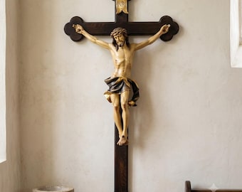 May include: A dark brown wooden crucifix featuring a carved figure of Jesus with a light skin tone, wearing a crown of thorns and a dark cloth. A small gold-colored plaque at the top of the cross displays the letters INRI in black text.
