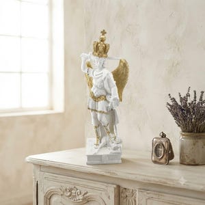 May include: A white and gold statue of an archangel wearing a crown, holding a sword, and featuring large wings. The figure stands on a rectangular base, depicted in a dynamic pose with detailed armor accents in a metallic gold finish.