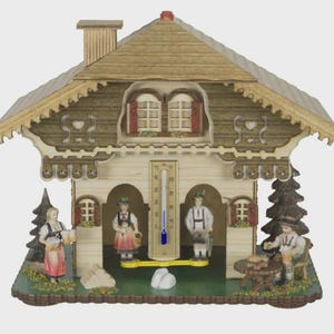 May include: A decorative wooden chalet-style thermometer with miniature figures in traditional attire. The chalet features a detailed roof, windows with red shutters, and a thermometer with a blue indicator. Figures include a woman with beer steins and a man seated at a table.