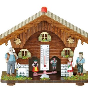 May include: A wooden chalet-style thermometer with a pitched roof and decorative carvings. Miniature figures in traditional attire stand around the base. The thermometer displays both Celsius and Fahrenheit scales. The chalet is brown with a red top.