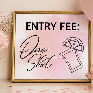 Puede incluir: Un letrero cuadrado en un marco dorado con un fondo de acuarela rosa claro. El texto dice ENTRY FEE: One Shot en letras negras. Junto al texto hay un dibujo lineal negro de un gajo de lima sobre el borde de un vaso de chupito rectangular.