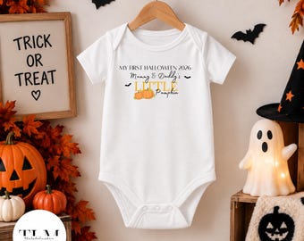 Puede incluir: Un body blanco de manga corta para bebé con el texto MY FIRST HALLOWEEN 2026, Mummy & Daddy's LITTLE Pumpkin y una ilustración de dos calabazas naranjas. La prenda tiene un cuello redondo y cierres a presión en la parte inferior.