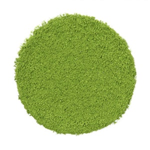 Könnte beinhalten: Nahaufnahme eines Haufens grünen Matcha-Pulvers auf einer weißen Oberfläche.