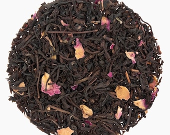 May include: A close-up of a blend of black tea leaves and dried rose petals. The tea is a dark brown color and the petals are a light pink.