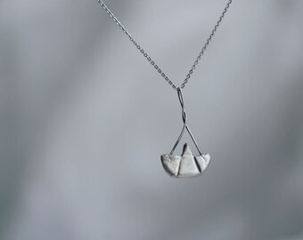 May include: A silver necklace with a small, origami-style boat pendant.