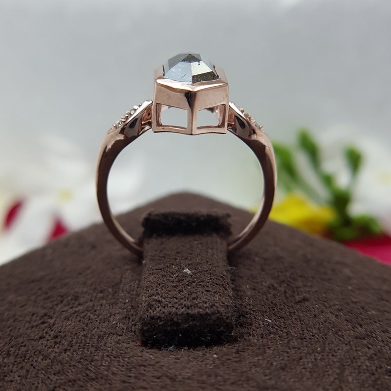 May include: A rose gold ring with a large, dark gray, octagon-shaped gemstone. The ring is set with smaller diamonds on the band.