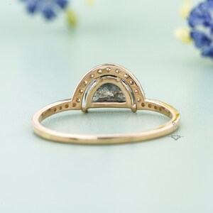 May include: A gold ring with a half-moon shaped grey gemstone surrounded by a double row of smaller diamonds.