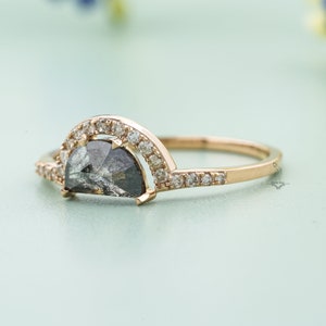 May include: A gold ring with a half-moon shaped black diamond set in a halo of smaller diamonds.