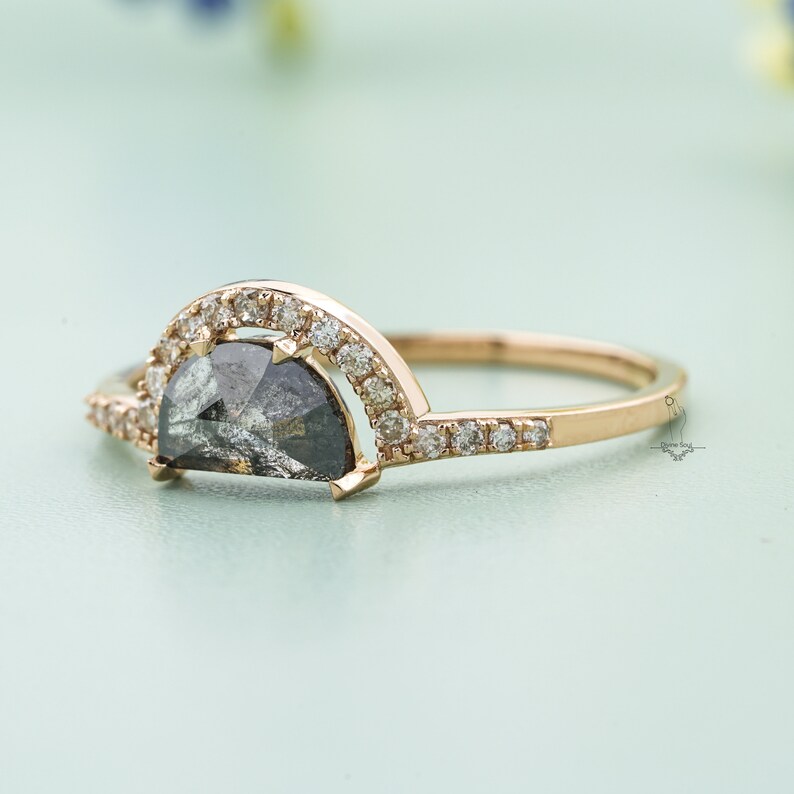 May include: A gold ring with a half-moon shaped black diamond set in a halo of smaller diamonds.