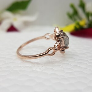 May include: A rose gold ring with a large, clear, faceted gemstone set in a delicate, ornate setting.