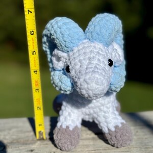 May include: A handmade crochet ram figurine. The ram is primarily white with light blue horns and accents. The ram's hooves are gray. The figurine is approximately 6 inches tall.