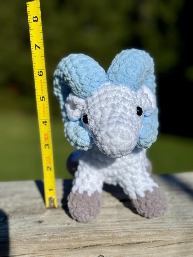 May include: A handmade crochet ram figurine. The ram is primarily white with light blue horns and accents. The ram's hooves are gray. The figurine is approximately 6 inches tall.