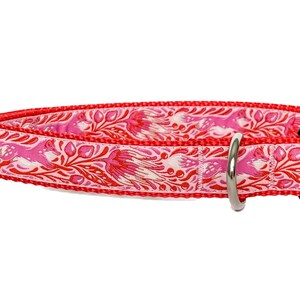 May include: A pink and red dog collar with a floral pattern and a silver metal buckle.
