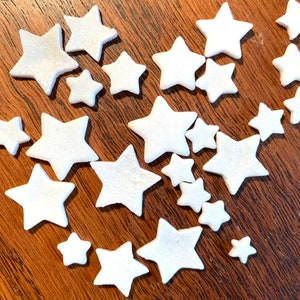 May include: A collection of white star-shaped decorations scattered on a wooden surface.