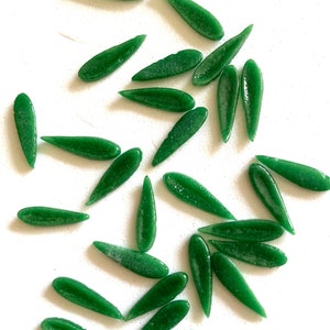 May include: A collection of green glass teardrop-shaped beads. The beads have a sparkly, iridescent finish.