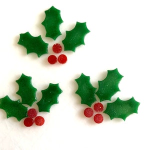 Peut inclure: Vue aérienne de trois brins de houx, chacun composé de trois feuilles vertes et de trois baies rouges. Les feuilles ont une texture et les baies sont petites et rondes. Fond blanc.