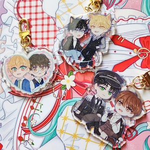 Puede incluir: Una colección de llaveros acrílicos de estilo anime con personajes de dibujos animados. Los llaveros tienen cierres dorados y representan parejas de personajes con diferentes atuendos. Algunos llaveros tienen forma de corazón, otros son rectangulares.