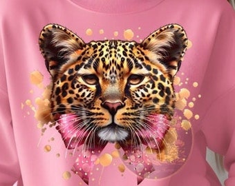 May include: Pink sweatshirt featuring a detailed leopard face design. The leopard has a spotted coat, with pink accents and a bow. The sweatshirt is a solid pink color, with long sleeves and a crew neck.