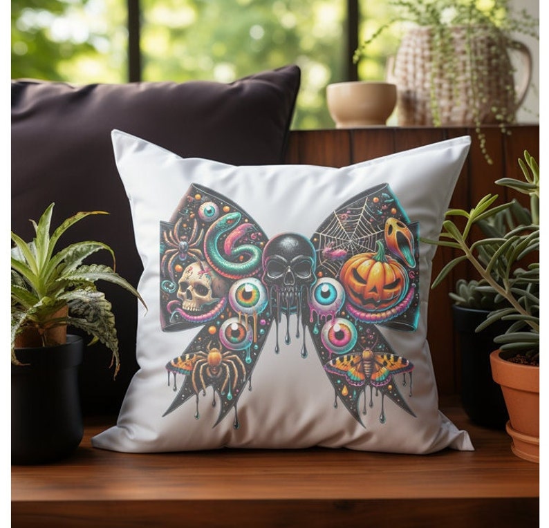 May include: A white pillow featuring a black and colourful bow design. The bow is decorated with a skull, eyeballs, a snake, a spider, a pumpkin, and a moth.