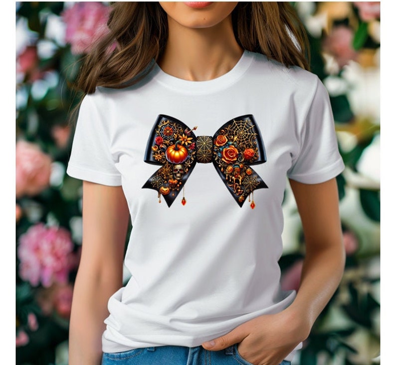 May include: White t-shirt featuring a black bow decorated with Halloween-themed embellishments, such as pumpkins, spiders, and skulls.