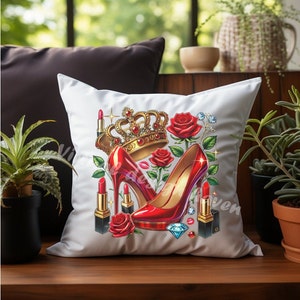 Puede incluir: Almohada blanca con un zapato de tac&oacute;n alto rojo, una corona dorada, rosas rojas y l&aacute;piz labial rojo sobre un fondo blanco.