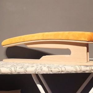 May include: A wooden ironing board with a yellow padded top. The board is designed to be used on top of a standard ironing board.