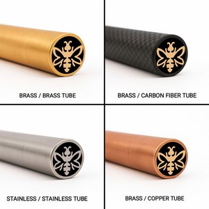 Könnte beinhalten: Vier zylindrische Rohre mit einem Bienenlogo an den Enden. Die Rohre sind aus Messing, Kohlefaser, Edelstahl und Kupfer. Der Text auf dem Bild lautet: BRASS / BRASS TUBE, BRASS / CARBON FIBER TUBE, STAINLESS / STAINLESS TUBE und BRASS / COPPER TUBE.