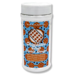 May include: A cylindrical, clear plastic container with a white lid. The label features a blue background with chocolate chip cookie illustrations. Text on the label reads "Chocolate Chip Cookie Dough" and "Carpet Deodorizer".