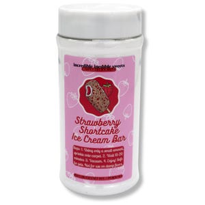 May include: A white cylindrical container with a white lid, featuring a pink label with text and a strawberry shortcake ice cream bar graphic. The label reads "Strawberry Shortcake Ice Cream Bar" and includes usage instructions.