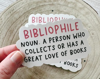 May include: White sticker with pink text that reads "Bibliophile Noun. A person who collects or has a great love of books".
