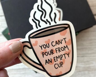 May include: A pink coffee mug with a black outline and hearts printed on it. The mug has steam coming from it and the text "You can't pour from an empty cup" is printed on the mug.