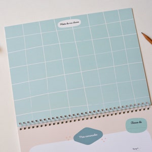 May include: A light blue gridded page with the text "Photo de ma classe" in a white oval. The page is part of a spiral bound notebook with a beige background and the text "Mes camarades" and "Classe de" in white.