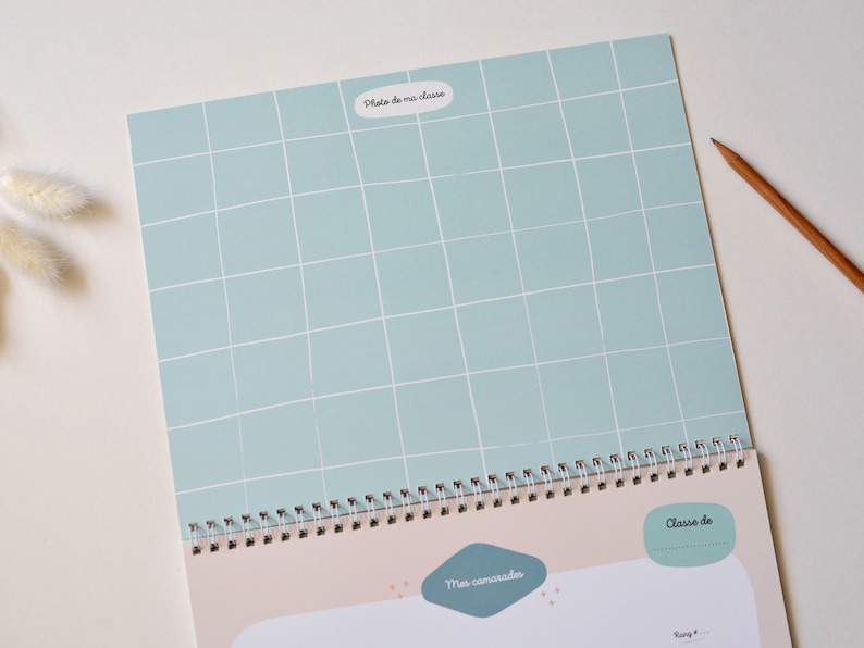 May include: A light blue gridded page with the text "Photo de ma classe" in a white oval. The page is part of a spiral bound notebook with a beige background and the text "Mes camarades" and "Classe de" in white.