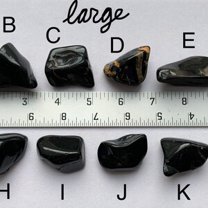 A photo of all of the large stones, labelled with their corresponding letters, lined up against a ruler (in inches). Stones A, B, C, D, E, and F are shown above the ruler and stones G, H, I, J, K, and L are shown below it.