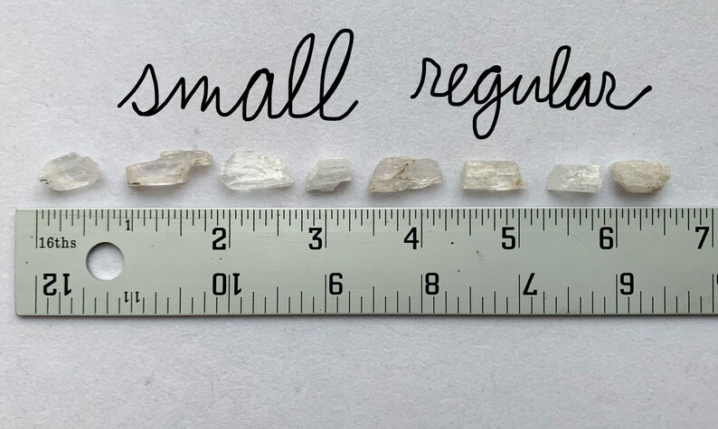A photo of all of the small regular stones lined up against a ruler (in inches).