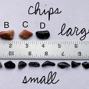 A photo of all of the "chips" stones lined up against a ruler (in inches). The "large chips" are shown above the ruler, labelled with their corresponding letters, and the "small chips" are shown below it.