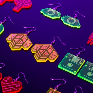May include: A selection of neon acrylic earrings in diverse geometric and tech-inspired designs. The earrings feature shapes such as hearts, circuit boards, and retro computer components, all with silver hooks, against a dark purple backdrop.