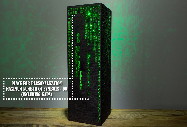 May include: A black wooden lamp with a green light shining through the cut-out letters. The lamp has a place for personalization with a maximum of 90 symbols, including spaces.