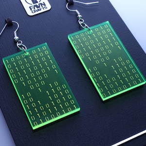 K&ouml;nnte beinhalten: Gr&uuml;ne, rechteckige Ohrringe mit eingraviertem Bin&auml;rcode. Die Ohrringe haben silberfarbene Haken und werden auf einer schwarzen Oberfl&auml;che pr&auml;sentiert. Der Text "FAVN CRAFTS" ist sichtbar.