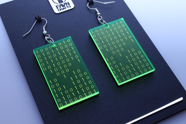 K&ouml;nnte beinhalten: Gr&uuml;ne, rechteckige Ohrringe mit eingraviertem Bin&auml;rcode. Die Ohrringe haben silberfarbene Haken und werden auf einer schwarzen Oberfl&auml;che pr&auml;sentiert. Der Text "FAVN CRAFTS" ist sichtbar.
