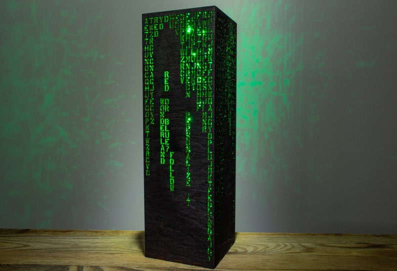 May include: A black wooden lamp with a green light shining through the cut-out letters. The letters spell out words like "red", "blue", "follow", and "personalize".