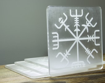 May include: A set of four clear acrylic coasters with a white etched design of a compass rose. The coasters are stacked on top of each other.