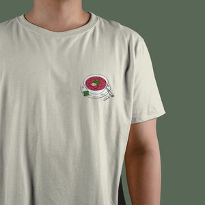 Peut inclure: Un t-shirt blanc avec un dessin d'un bol de soupe rouge à la betterave avec une garniture verte et une cuillère. Le texte "Love" est écrit sous le bol.