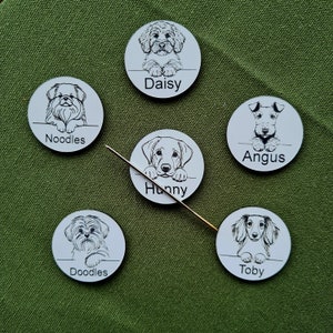 May include: Five white round dog name tags with black outlines of dogs and their names. The names are Daisy, Noodles, Hunny, Angus, and Toby.