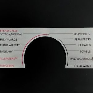 May include: A white washing machine control panel with a circular dial and a list of wash cycles, including *STEAM CYCLE, COTTON/NORMAL, BULKY/LARGE, BRIGHT WHITEST™, SANITARY, ALLERGIENETM, TUB CLEAN, HEAVY DUTY, PERM.PRESS, DELICATES, TOWELS, HAND WASH/WOOL, and SPEED WASH.