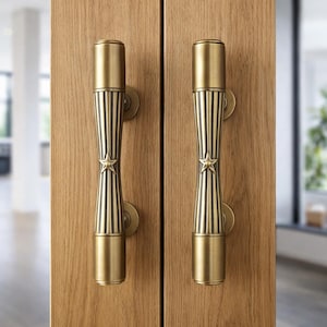 Puede incluir: Dos manijas de puerta de latón antiguo con diseño de estrella. Las manijas son cilíndricas con ranuras verticales y una estrella en el centro. Están montadas en una puerta de madera marrón claro. Las manijas tienen un estilo vintage y decorativo.