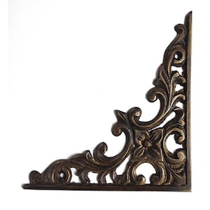 May include: Ornate brass corner bracket with a floral design. The bracket is a right angle and has a decorative, intricate pattern.