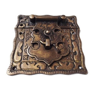 May include: Antique brass latch with intricate floral designs and a decorative keyhole. The latch has a square shape with rounded corners and a slightly raised edge.