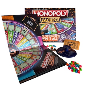 Può includere: Gioco da tavolo Monopoly Jackpot. L'immagine mostra la scatola e il tabellone di gioco con un design colorato, il logo e il testo del gioco. Include pedine, dadi e denaro di gioco. Il tabellone presenta una ruota con opzioni di pagamento.